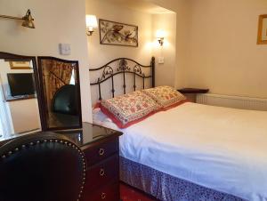 a bedroom with a bed and a dresser with a mirror at Stow Lodge Hotel in Stow on the Wold