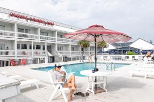 a woman sitting in a chair under an umbrella next to a pool at Shem Creek Inn in Charleston