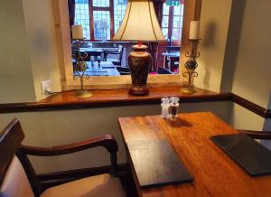 a dining room table with a lamp and a window at Stow Lodge Hotel in Stow on the Wold