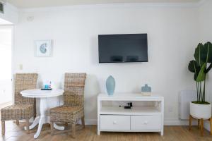 a living room with a table and a tv on a wall at Molloy Gulf Motel & Cottages in St. Pete Beach