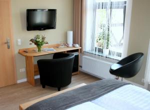 a bedroom with a desk with two chairs and a television at Pension "Westphal's" in Wismar