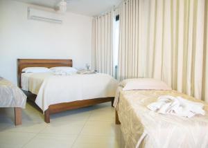 - une chambre avec 2 lits et des serviettes blanches dans l'établissement Pousada Vieira, à Arraial do Cabo