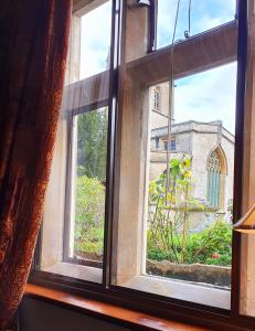 an open window with a view of a church at Stow Lodge Hotel in Stow on the Wold