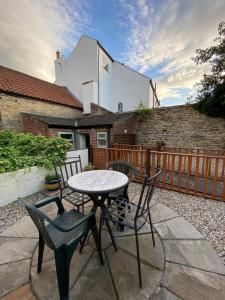 eine Terrasse mit einem Tisch, Stühlen und einem Zaun in der Unterkunft Bondgate Holiday Cottage in Durham