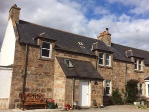 una vieja casa de ladrillo con un banco delante de ella en Lettoch Farm en Dufftown