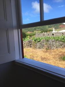 een raam met uitzicht op een stenen muur bij Graciosa Family House in Santa Cruz da Graciosa