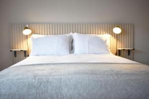 a bed with white pillows and two lights on it at 5a Bank Street in Keswick