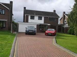 dos coches estacionados en una entrada de entrada en frente de una casa en Almost Heaven, en Acton Trussell