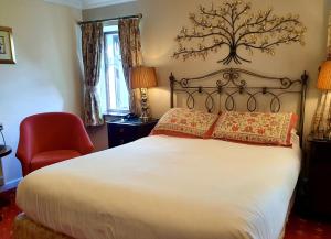 a bedroom with a large bed and a red chair at Stow Lodge Hotel in Stow on the Wold