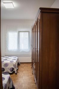 een slaapkamer met een bed en een houten kast bij Apartamento PLAYA ESTEIRO in Muros