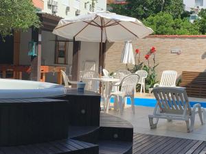 佛羅安那波里的住宿－Beach House Floripa，庭院配有遮阳伞和桌椅。