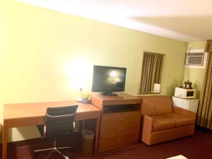Habitación de hotel con escritorio, TV y silla en Valley Inn Motel, en Sudbury