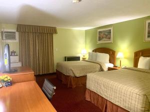 Habitación de hotel con 2 camas y escritorio en Valley Inn Motel, en Sudbury