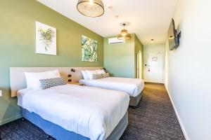 two beds in a room with green walls at Nightcap at Commercial Hotel in Gold Coast