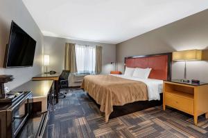 Quality Inn & Suites Evansville Downtown في إيفانسفيل: غرفة فندقية بسرير وتلفزيون بشاشة مسطحة