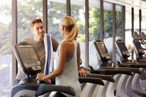 a man and woman walking on treadmills in a gym at RACV Royal Pines Resort Gold Coast in Gold Coast