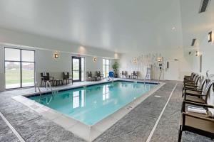 a large swimming pool in a room with chairs at Sleep Inn & Suites Ames near ISU Campus in Ames