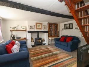 a living room with two blue couches and a fireplace at Apple Tree Cottage in Burton Bradstock