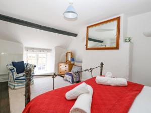 a bedroom with a red bed and a mirror at Apple Tree Cottage in Burton Bradstock