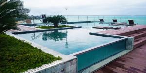 a swimming pool with a view of the ocean at Pajuçara Front Beach in Maceió