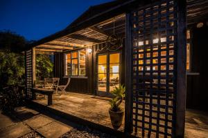 una pequeña casa con terraza de madera por la noche en Corru Gate en Mapua