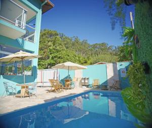 a swimming pool with chairs and umbrellas next to a house at Residencial Águas de Bare in São Sebastião