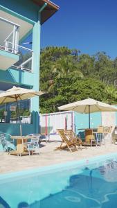 聖塞巴斯蒂安的住宿－Residencial Águas de Bare，一组椅子和遮阳伞,位于游泳池旁