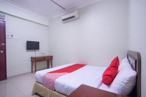 een slaapkamer met een bed met rode kussens en een tafel bij Super OYO 89363 Casavilla Hotel in Batu-grotten