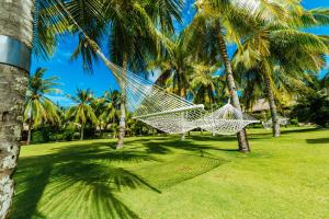 a hammock hanging between palm trees in a park at Bohol Beach Club in Panglao Island