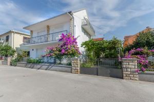 a white house with flowers on the side of it at Rooms Mira II in Vodice