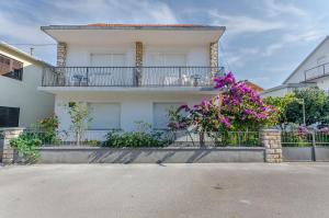 a white house with a balcony with purple flowers at Rooms Mira II in Vodice