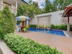 un patio trasero con piscina y una mesa con sombrilla en Collection O 3945 Bale Tardian Syariah, en Yogyakarta