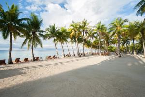 a beach with palm trees and people on it at Bohol Beach Club in Panglao Island