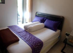1 cama con almohadas moradas y blancas y ventana en Hotel Mutiara Baru, en Batu