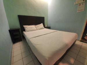 a bed with white sheets and pillows in a room at SPOT ON 89698 Budget Inn Hotel in Kuala Lumpur