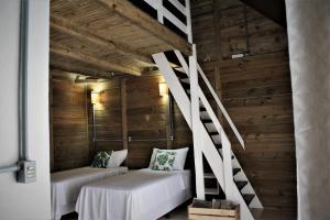 um quarto com paredes de madeira e uma escadaria com sofás brancos em Garten Chalés em Pomerode