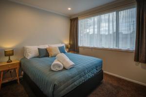 a bedroom with a bed with towels on it at Dusky Motels in Te Anau