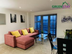 a living room with a red couch and a glass table at "Clarence Court Newcastle" by Greenstay Serviced Accommodation - Stunning 1 Bed Apt In City Centre With Parking & Balcony-Sleeps 4 - Perfect For Contractors, Business Travellers, Couples & Families - Fast Wi-Fi - Long Stays Welcome in Newcastle upon Tyne