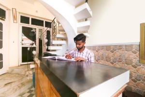 um homem sentado num balcão numa cozinha em OYO 64955 Arun Palace em Chandīgarh