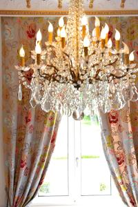 un lustre dans une chambre avec fenêtre dans l'établissement Grand Hôtel "Château de Sully" - Piscine & Spa, à Bayeux