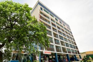 un grand bâtiment avec un arbre devant dans l'établissement OYO 458 Nakorn Siam Boutique, à Pattaya