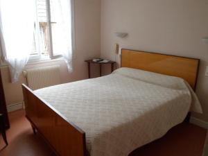 - une chambre avec un lit doté d'une tête de lit en bois et d'une fenêtre dans l'établissement Hotel de L'Hippodrome, à Arnac-Pompadour