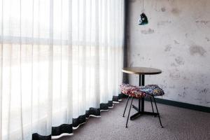 a table and a chair in front of a window at Ovolo Nishi in Canberra