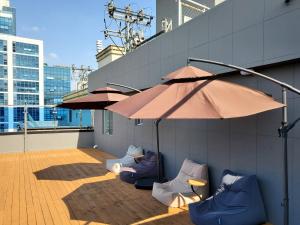 a patio with chairs and an umbrella on a building at The Stone Bridge Hotel Sasang in Busan
