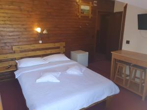 ein Schlafzimmer mit einem großen weißen Bett und einer Holzwand in der Unterkunft Pensiunea Melinda in Petroşani