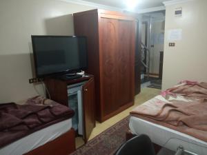 فندق المغربي في الإسكندرية: غرفة صغيرة تحتوي على تلفزيون وسرير وغرفة بها جهاز تلفاز