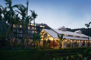un complexe avec un bâtiment éclairé et des palmiers dans l'établissement The Peri Hotel Khao Yai, à Phayayen