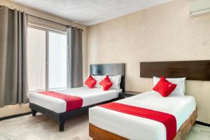 Gómez Palacio的住宿－Capital O Hotel La Siesta, Gomez Palacio，两张位于酒店客房的床铺,配有红色枕头