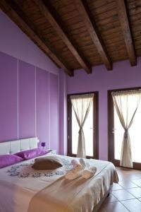 1 dormitorio con paredes moradas y 1 cama grande con 2 ventanas en La Corte D'Emilio B&B, en Vignola