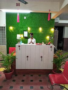 een man achter een toonbank met een groene muur bij Hotel Relax Inn in Nagpur